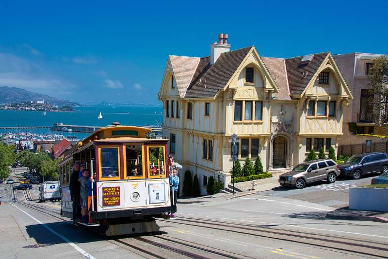 Photo of the famous cable car in San Francisco against the background of the island of Alcatraz.