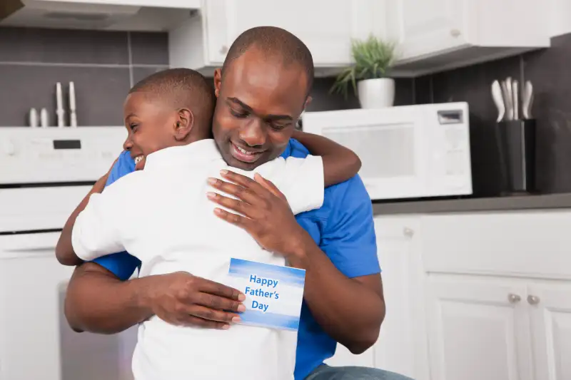 USA, Illinois, Metamora, Man embracing son (6-7), holding 'HappyFather's Day' card