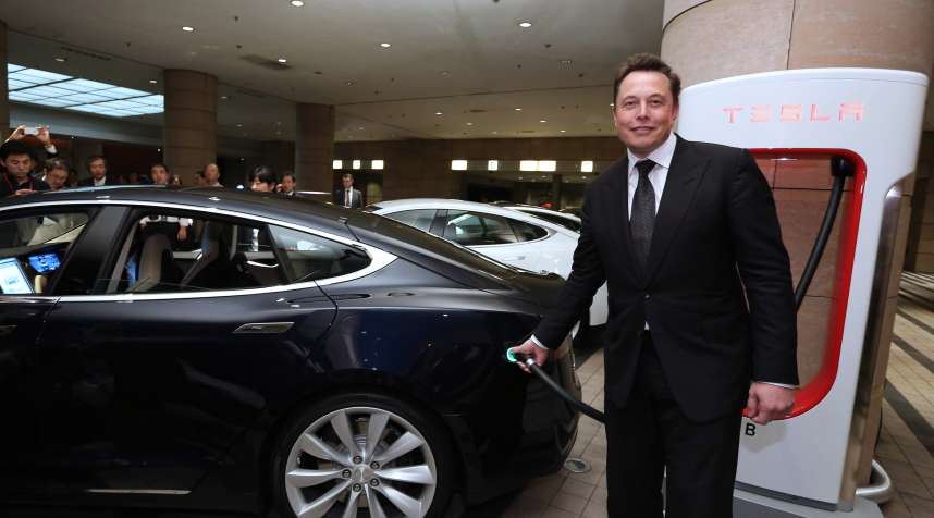 Elon Musk, co-founder and chief executive officer of Tesla Motors Inc., holds the charging nozzle as he demonstrates the company's Model S electric sedan following a news conference in Tokyo, Japan, on Monday, Sept. 8, 2014. Tesla may partner with Toyota Motor Corp. again in the future, Musk said. Photographer: Yuriko Nakao/Bloomberg via Getty Images