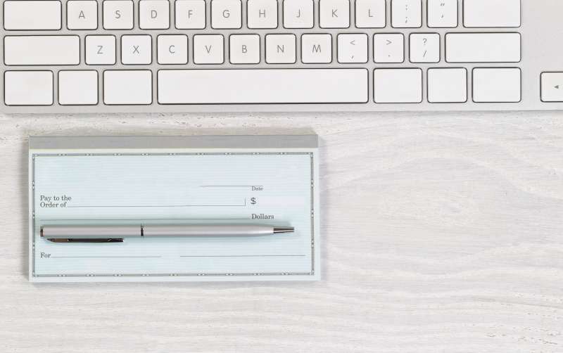 Blank checkbook with pen on white desktop