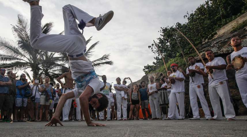 People gather to watch a capoeira performance along Arpoador rock, a popular tourist destination in Rio next to Ipanema beach, on February 28, 2016 in Rio de Janeiro,