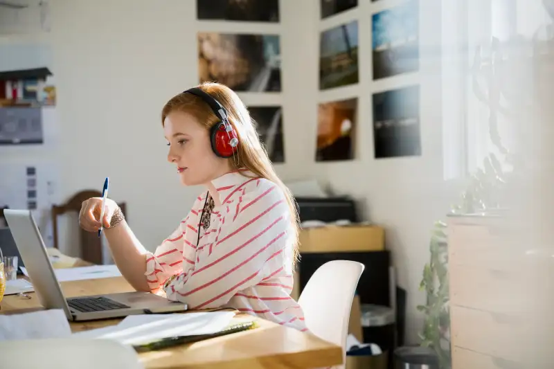 Designer with headphones working at laptop in office