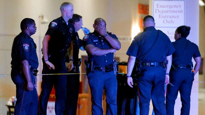 A Dallas police officer covers his face as he stands with others outside the emergency room at Baylor University Medical Center, Friday, July 8, 2016, in Dallas. Snipers opened fire on police officers in the heart of Dallas on Thursday night, killing some of the officers.