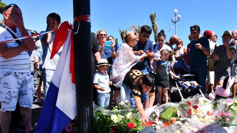 People visit the scene and lay tributes to the victims of a terror attack on the Promenade des Anglais on July 15, 2016 in Nice, France. A French-Tunisian attacker killed 84 people as he drove a lorry through crowds, gathered to watch a firework display during Bastille Day celebrations.