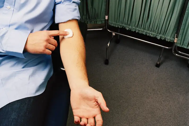 Young man holding cotton ball on arm