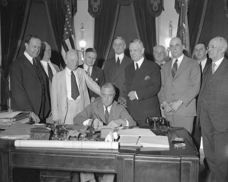 President Franklin D. Roosevelt signs the Banking Bill at the White House, June 16, 1933, surrounded by sponsors of the measure. From left: Sen. A.W. Barkley of Kentucky; Thomas P. Gore of Oklahoma; Carter Glass of Virginia; J.F.T. O'Connor, comptroller of currency; Sen. William G. McAdoo; Rep Henry B. Steagall of Alabama; Sen. D.U. Fletcher of Florida; and Rep. T. Alan Goldsborough of Maryland.