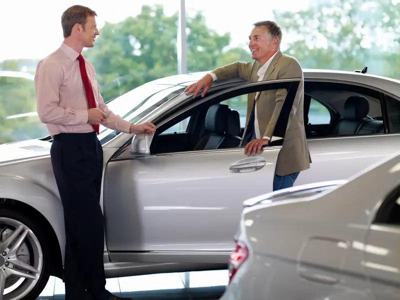 Salesman talking man in automobile showroom