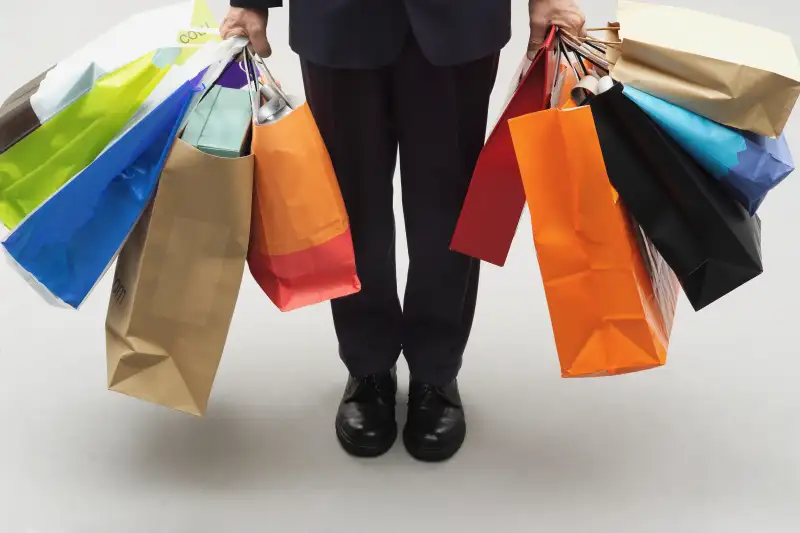 Mature man holding assorted shopping bags, low section