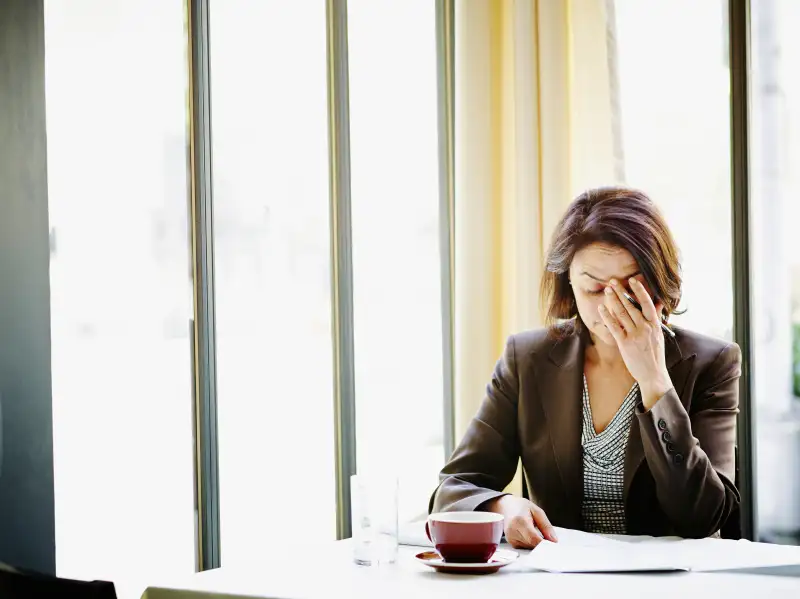 Businesswoman at table with head resting on hand