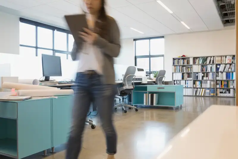 Businesswoman walking with digital tablet in office