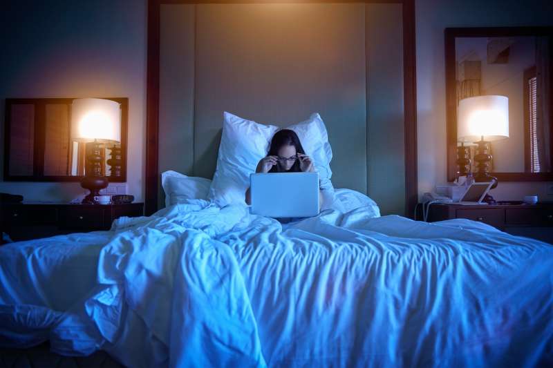 Pacific Islander woman using laptop in bed