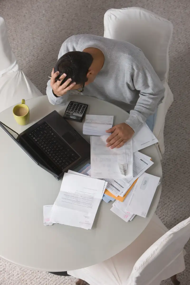 Overhead view of frustrated Hispanic man paying bills
