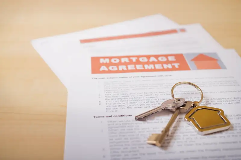 House keys and mortgage loan agreement on desk, close-up (differential focus)