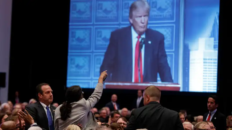 A demonstrator is led away as Republican presidential candidate Donald Trump delivers an economic policy speech to the Detroit Economic Club, Monday, Aug. 8, 2016, in Detroit.