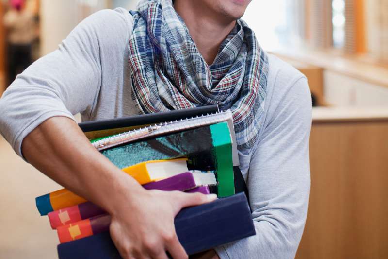 student rushing with stack of books