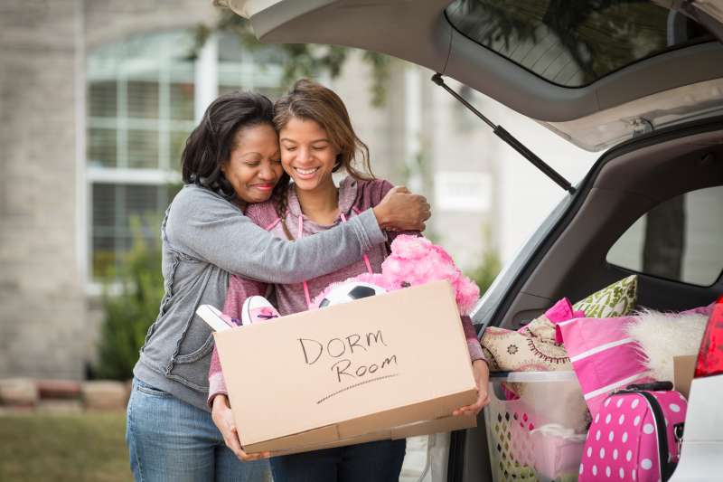 African American mother helping daughter pack for college
