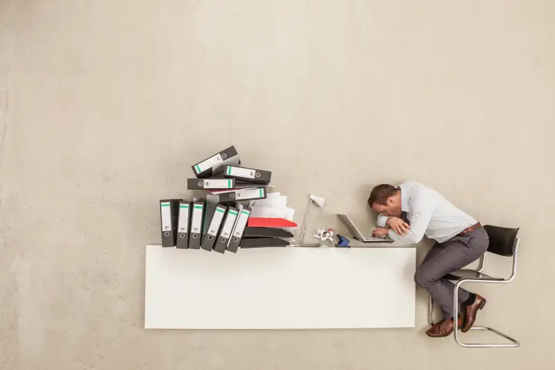 Businessman sleeping on office desk with stack of files