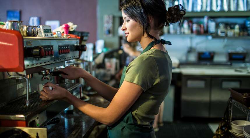 Teenage waitress preparing coffee in cafe kitchen