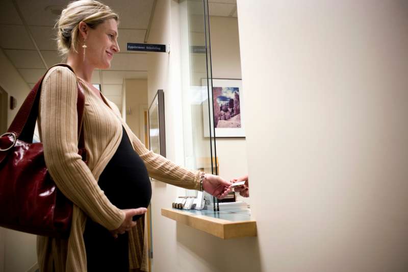 Pregnant woman standing at doctor office reception window