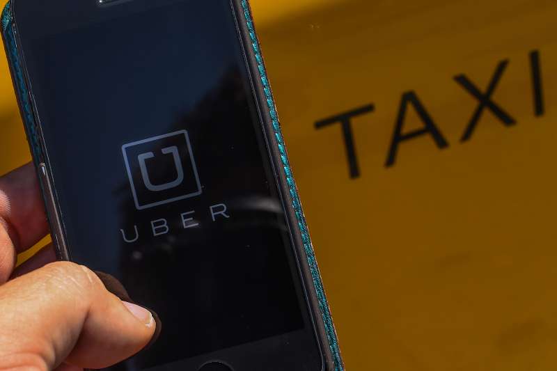 BARCELONA, SPAIN - JULY 01:  In this photo illustration, the new smart phone app 'Uber' logo is displayed on a mobile phone next to a taxi on July 1, 2014 in Barcelona, Spain. Taxi drivers in main cities strike over unlicensed car-halling services. Drivers say that is a lack of regulation behind the new app.  (Photo Illustration by David Ramos/Getty Images)