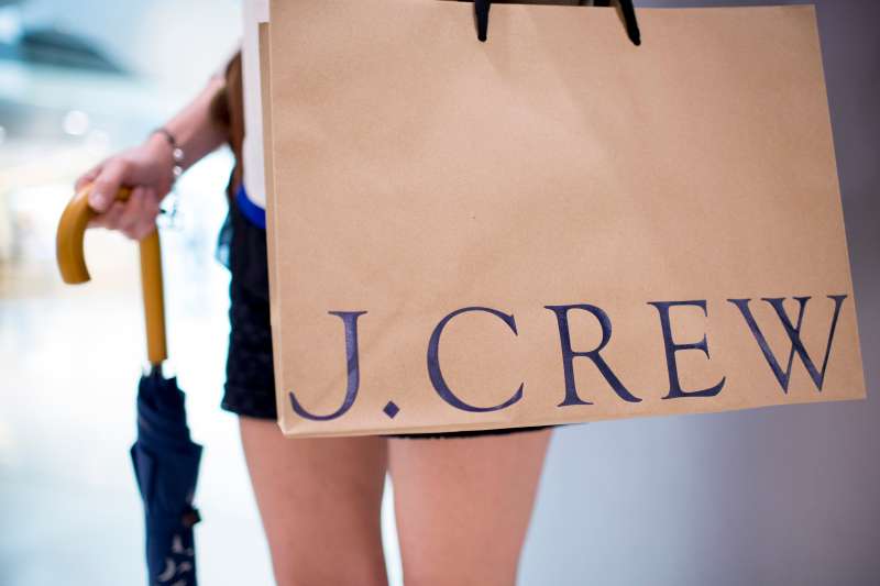 A woman poses for a photograph with a bag outside of J. Crew Group Inc.'s new women's store inside the International Finance Centre (IFC) mall in Hong Kong, China, on Thursday, May 22, 2014. J. Crew, the retail chain that opened its first Asian stores today, plans to expand its international push with outlets in continental Europe and will be scouting for locations in Paris. Photographer: Brent Lewin/Bloomberg via Getty Images