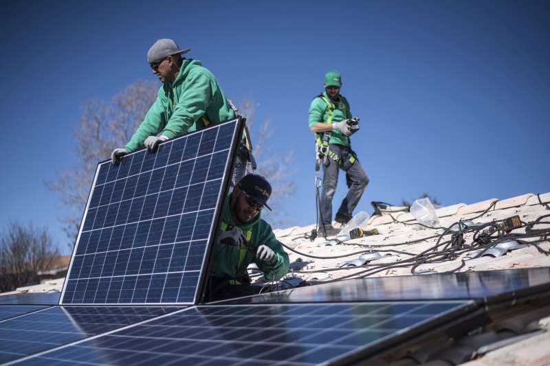 Workers secure solar panels to a rooftop during a SolarCity Corp. residential installation in Albuquerque, New Mexico, on Feb. 8, 2016.