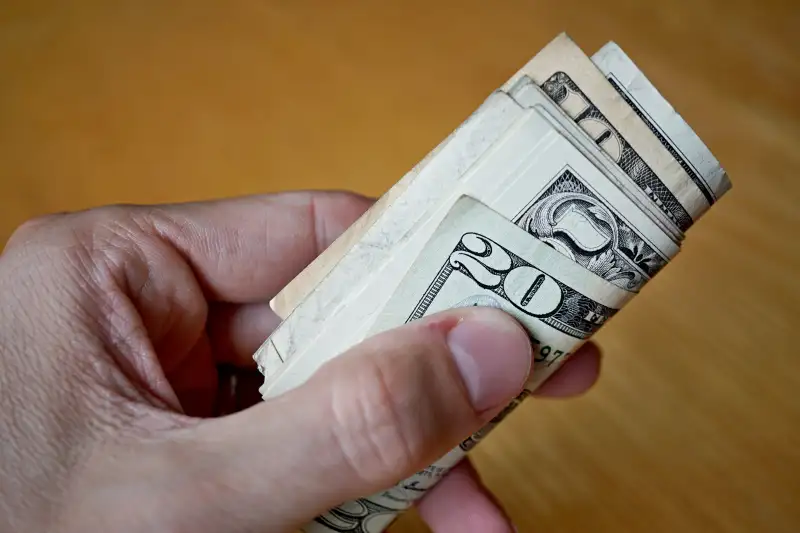 Roll of paper banknotes (American Dollars, USD) hold by hand