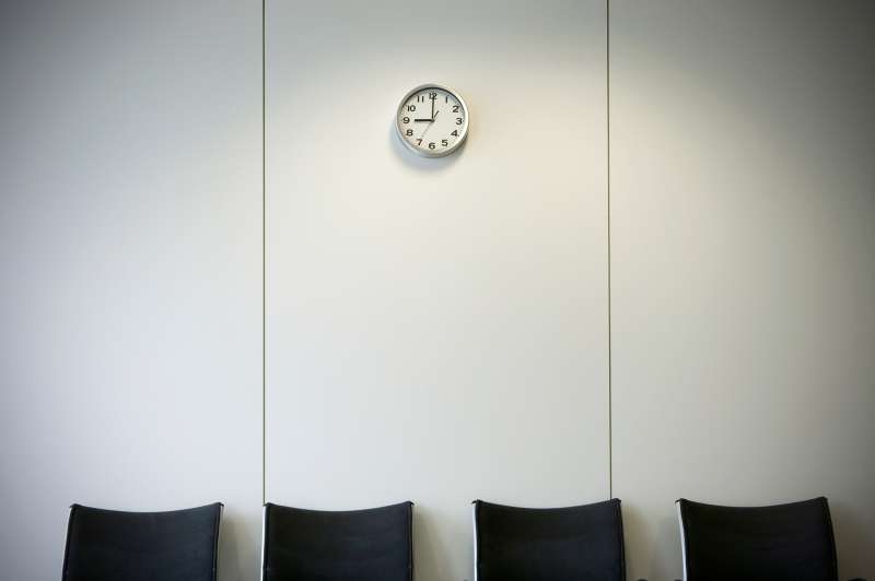 Row of chairs below wall clock in office waiting area