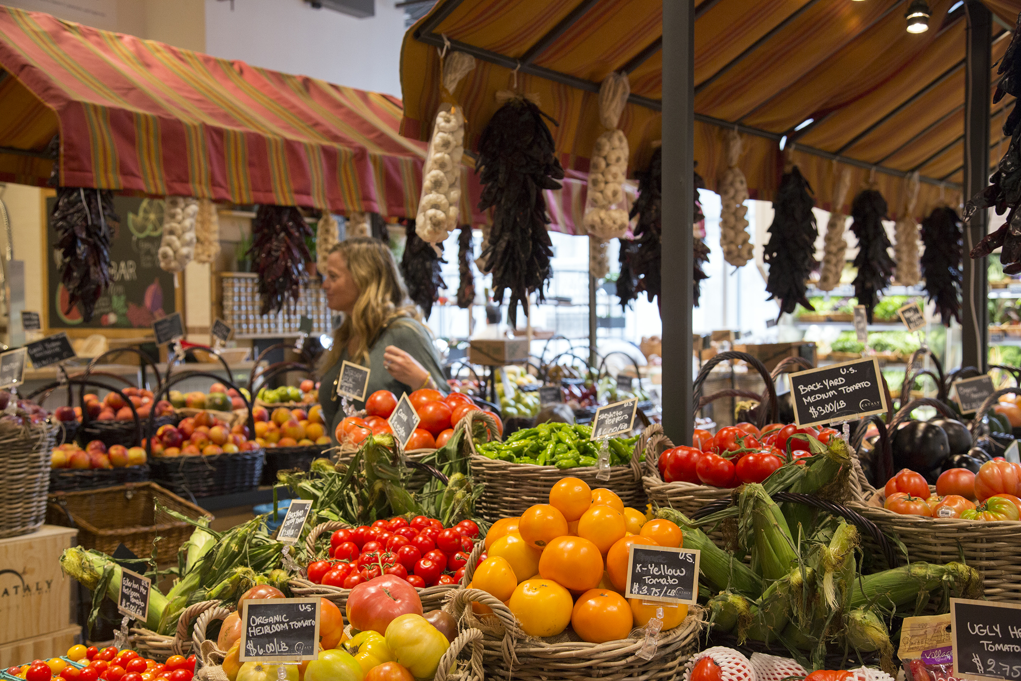 A woman selects fresh produce inside Eataly, Westfield World Trade, New York.