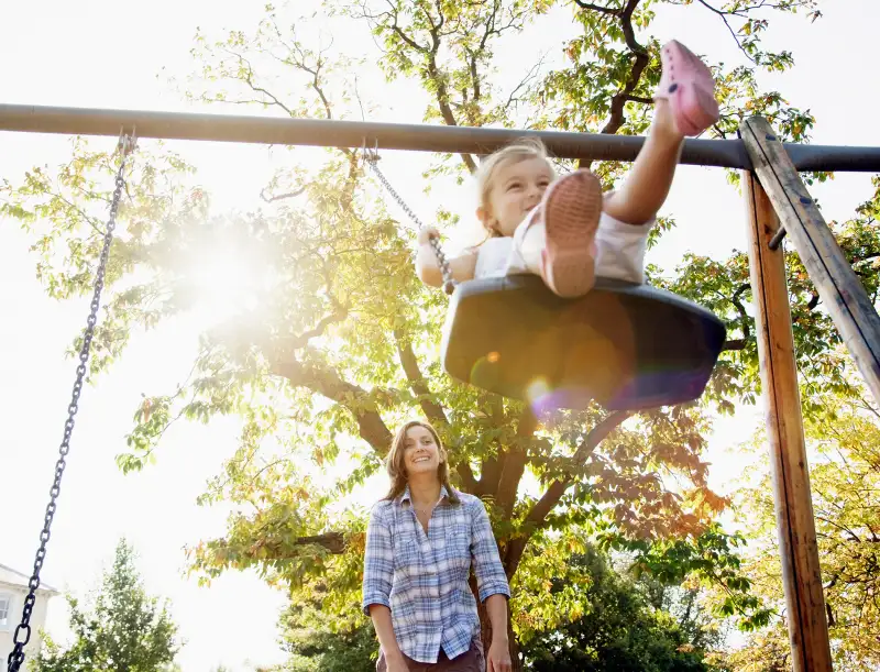 mother pushing daughter on swing