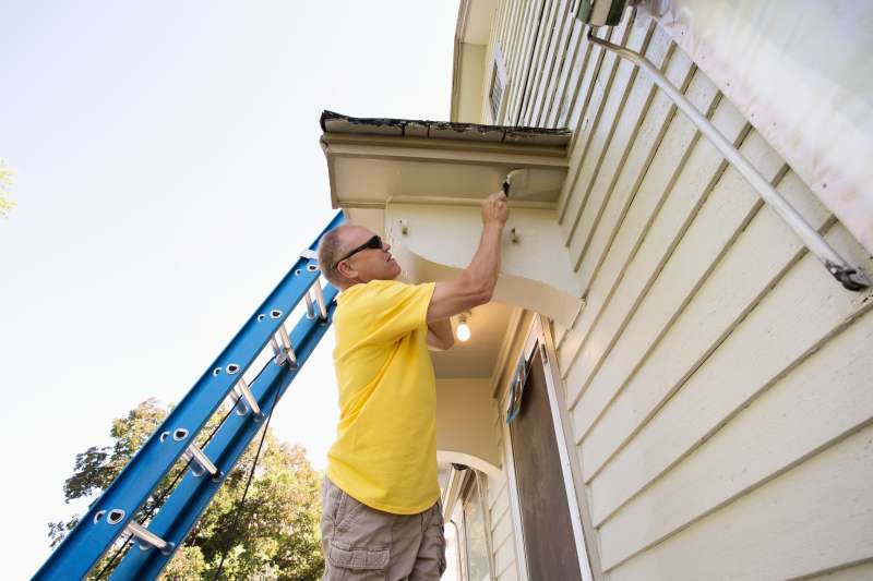 Caucasian man painting edge of house