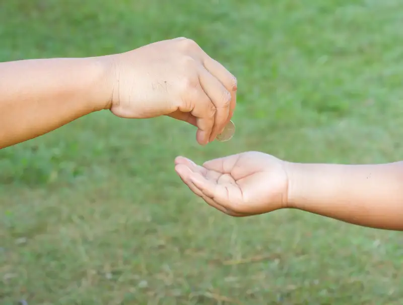 Hand gives coin to a boy