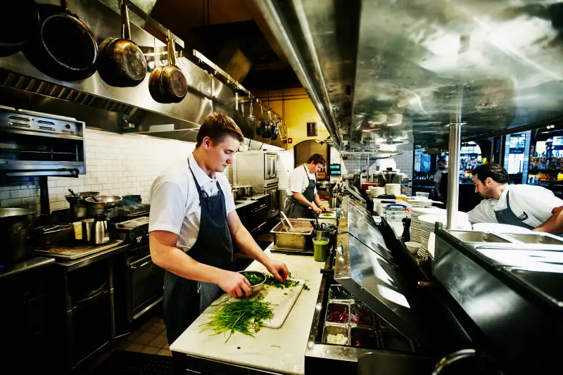 Line cook preparing cilantro in restaurant kitchen