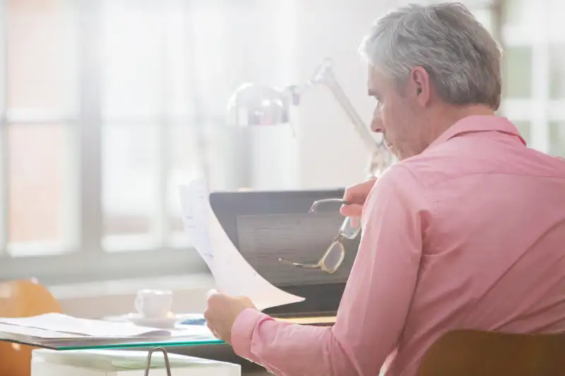 Businessman reading paperwork at home office desk