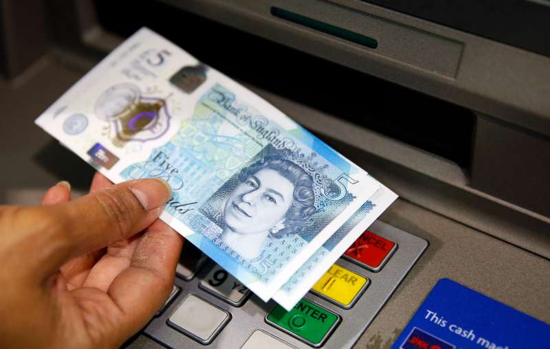 In this Sept. 13, 2016 file photo, a member of staff at a branch of Halifax bank, in London, displays a new British 5 pound sterling note, made from polymer, which is being launched Tuesday. The beleaguered British pound plummeted briefly to a fresh 31-year low Friday, Oct. 7, 2016, amid intensifying concerns about Britain's exit from the European Union. The pound tumbled nearly 6 percent in early Asian trading, falling as low as $1.1789, according to FactSet data.