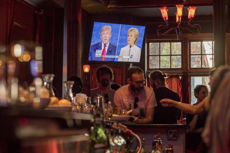 People watch as Donald Trump, 2016 Republican presidential nominee, and Hillary Clinton, 2016 Democratic presidential nominee, are seen on a television screen during a viewing party for the third U.S. presidential debate in San Francisco, California, on Oct. 19, 2016.
