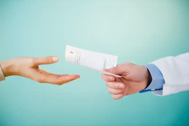 Close up of doctor's hand giving prescription to patient