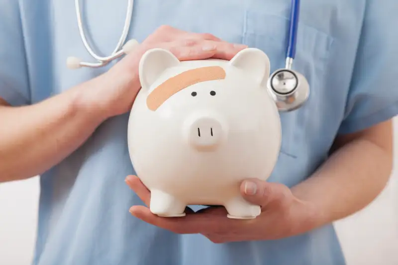 Nurse holding piggy bank, midsection