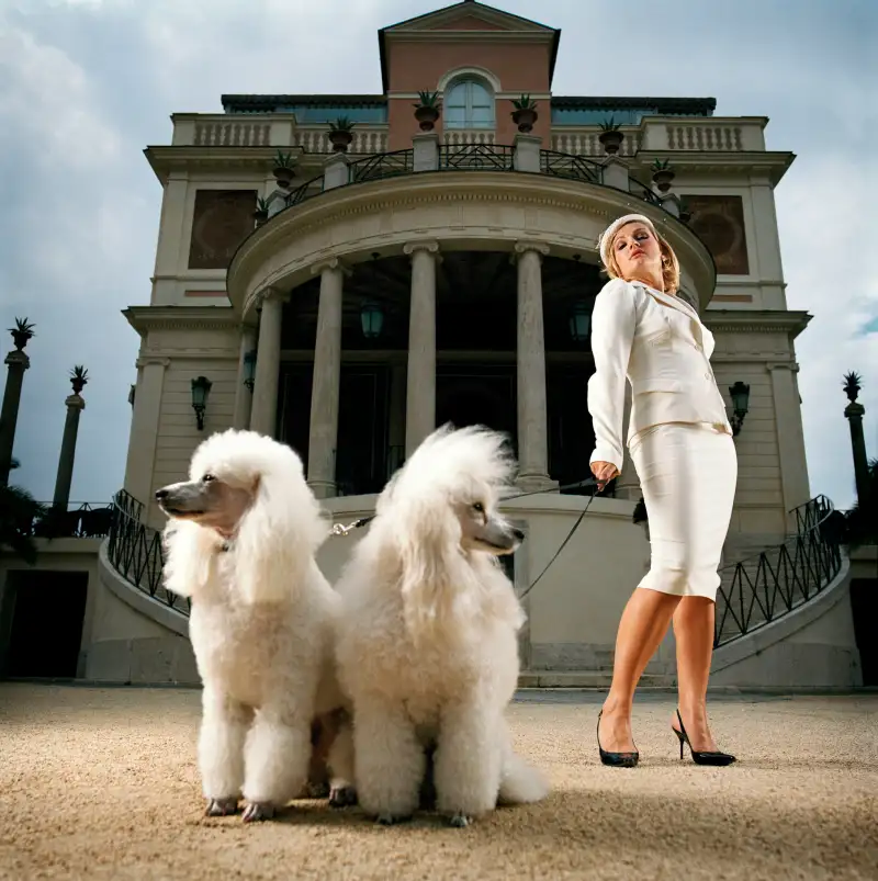 Woman and two poodles in front of building, low angle view