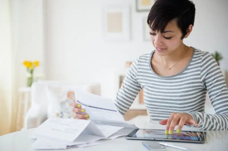 Mixed race woman paying bills on digital tablet
