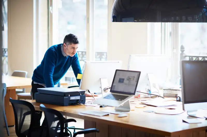 Businessman standing by desk working on a computer