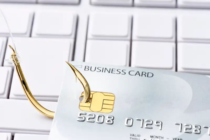 Close-up of credit card with fishing hook on computer keyboard