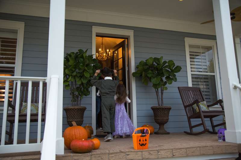 Brother and sister trick or treating at neighbours front door