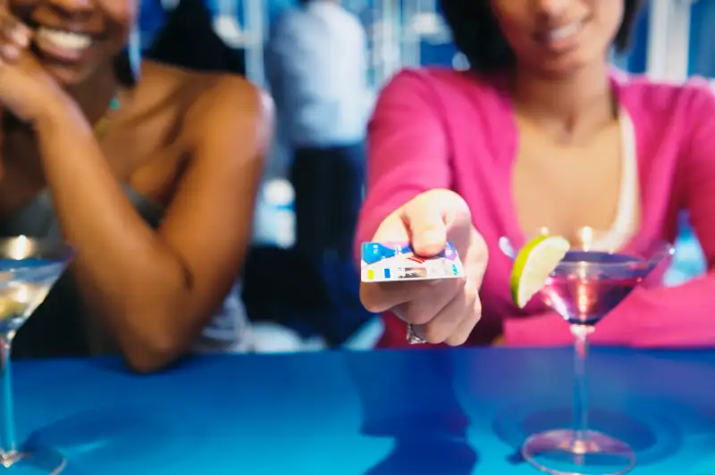 African woman handing credit card over bar