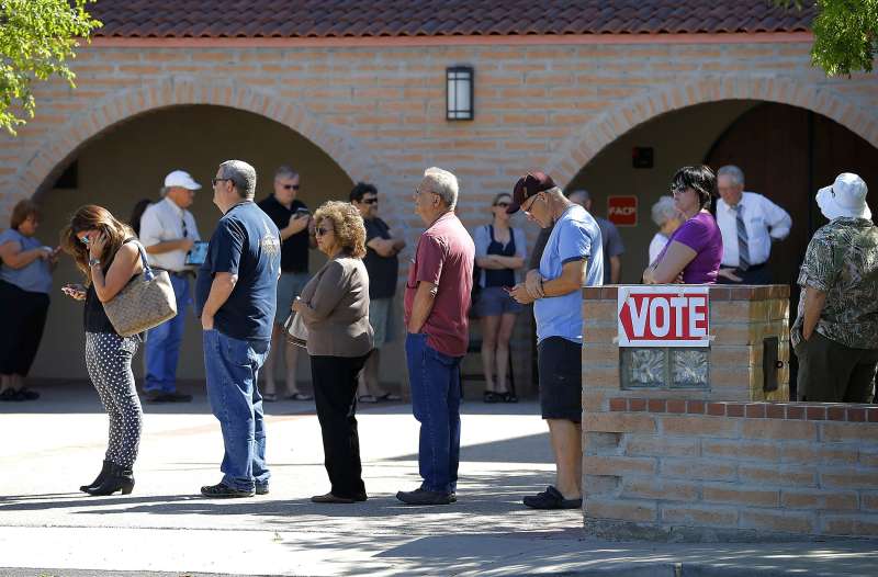In this March 22, 2016 photo, voters wait in line to cast their ballot in Arizona's presidential primary election in Gilbert, Ariz. New ID requirements.