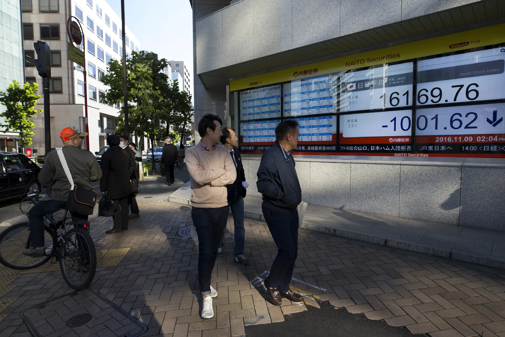 Pedestrians look at an electronic stock board displaying the Nikkei Stock Average outside a securities firm in Tokyo on Nov. 9, 2016. The yen strengthened against the U.S. dollar, which will make it more difficult for Japan to fight off its ongoing inflation problem.