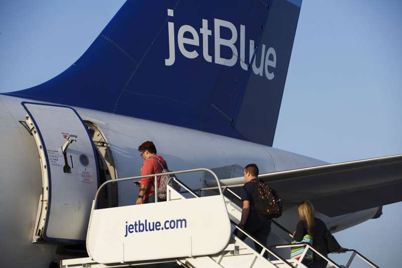 Travelers board a JetBlue plane.