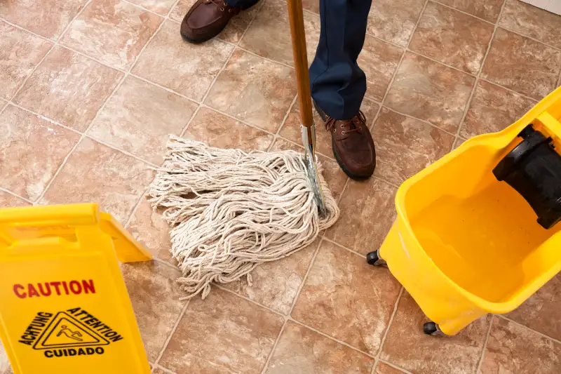 Caution sign, janitor man mopping floor of retail store. Cleaning.