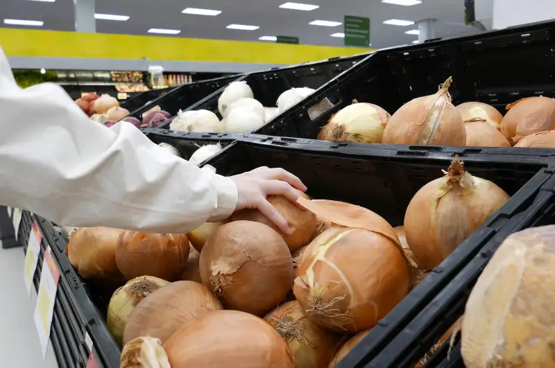 Woman picking fresh onion inside Walmart store