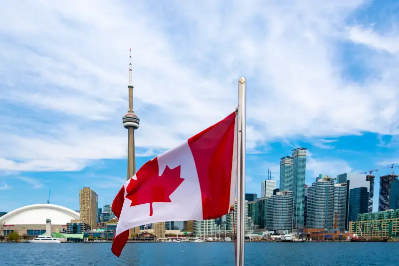 Canadian flag and the Toronto skyline. The flags waves from the back of a tourist cruise in Lake Ontario.